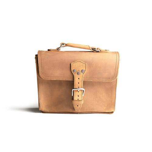 This is the front side of a tan brown leather satchel with a front pocket not angled.