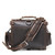 High quality back view with the strap of a dark brown rounded leather satchel.