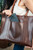High quality the women's work leather tote in dark brown showing the front view with cell phone
