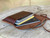 This is a red brown leather wallet bag with passports and yellow cards in it laying flat wide open.