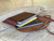 High quality red brown leather wallet bag with passports and yellow cards in it laying flat wide open.