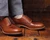 High quality natural tan full grain leather wing tip shoes studio three-quarter view on a wooden surface - Saddleback Leather