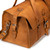 High quality tan brown leather duffle bag that has three straps to close it and has two round handles from the end.