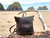 High quality this dark brown women's leather backpack is on a log at the beach.