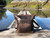 High quality this dark brown women's leather backpack is on a dock in Canada near Tofino and is showing the straight on shot.