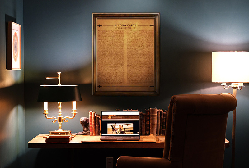 High quality framed copy of The Magna Carta burned into a large panel of aged looking tan leather hanging on an office wall.