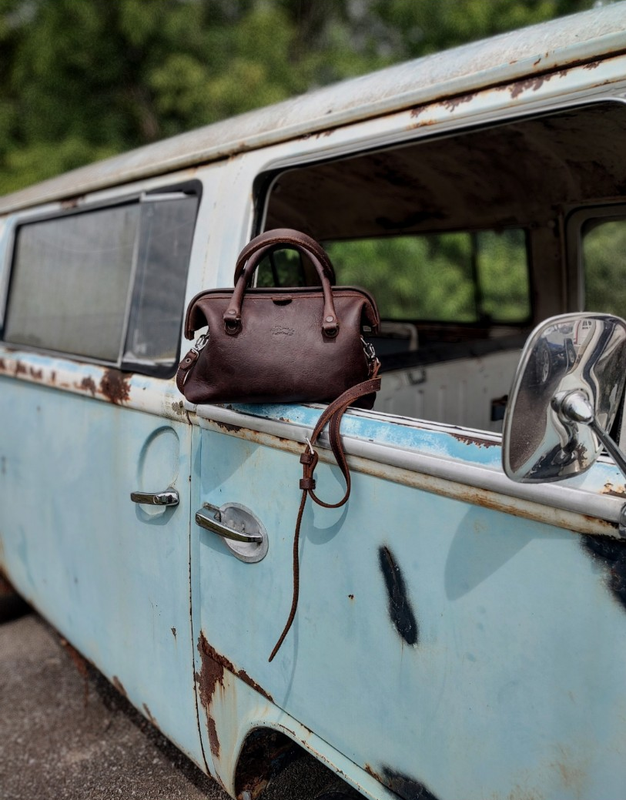 High quality the dark brown leather everyday purse on a vintage car. Made by Saddleback