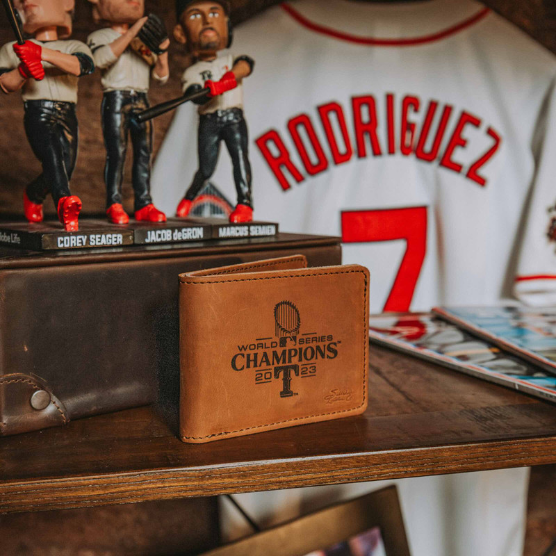 High quality immerse yourself in the Rangers legacy with this tan Saddleback leather wallet, prominently displayed alongside iconic memorabilia. It's an everyday tribute to the Texas Rangers' World Series victory, crafted for the true fan's enduring journey.