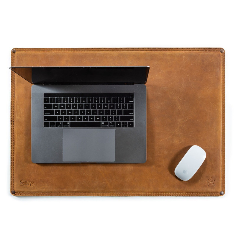 This is a leather desk pad with a laptop and a mouse on it.