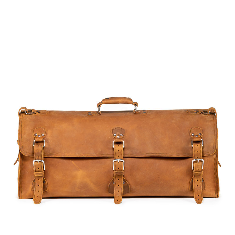 This leather duffle bag is tan brown and has three straps on it. It is showing the front side.