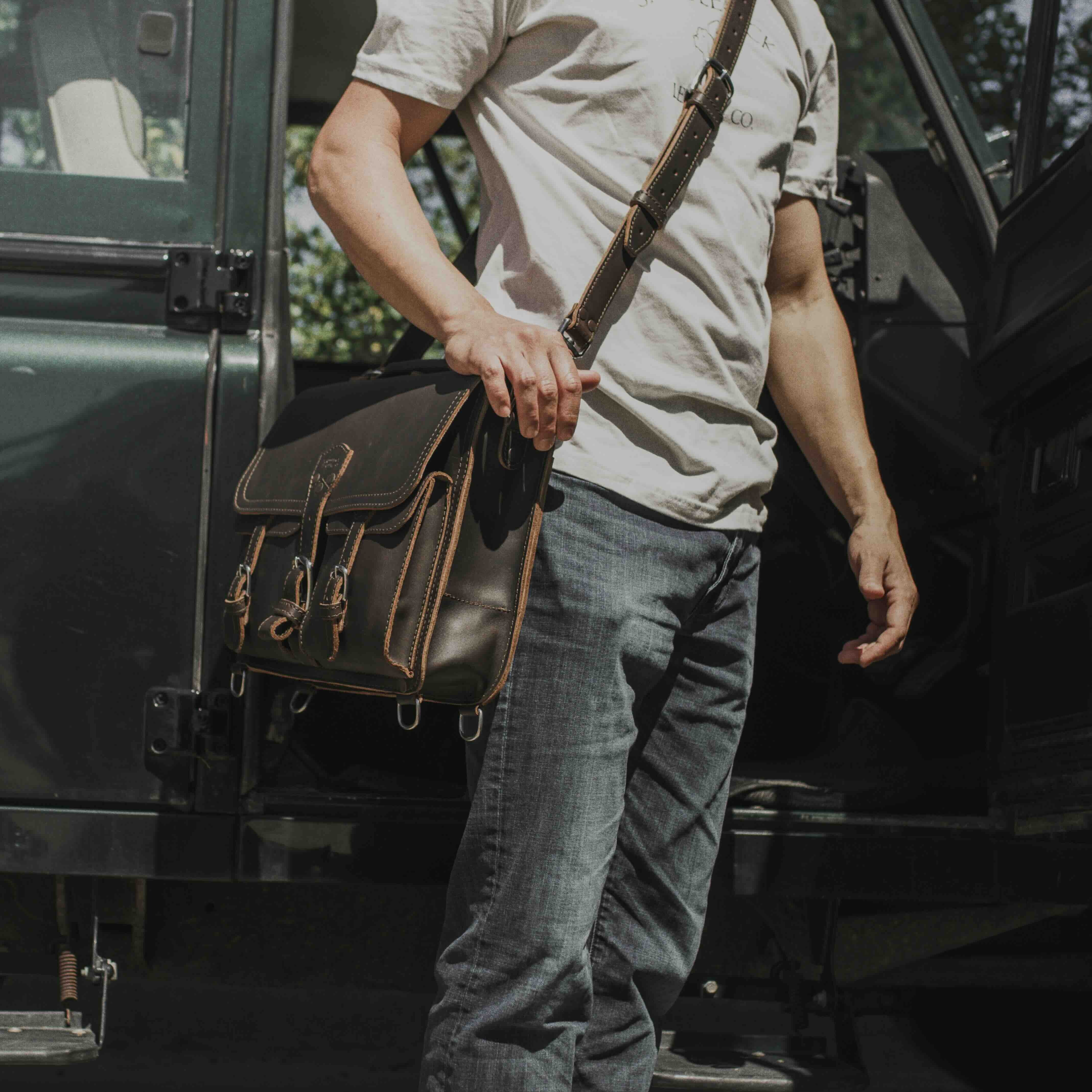 A man carrying a full grain leather briefcase over his shoulder with the shoulder strap.