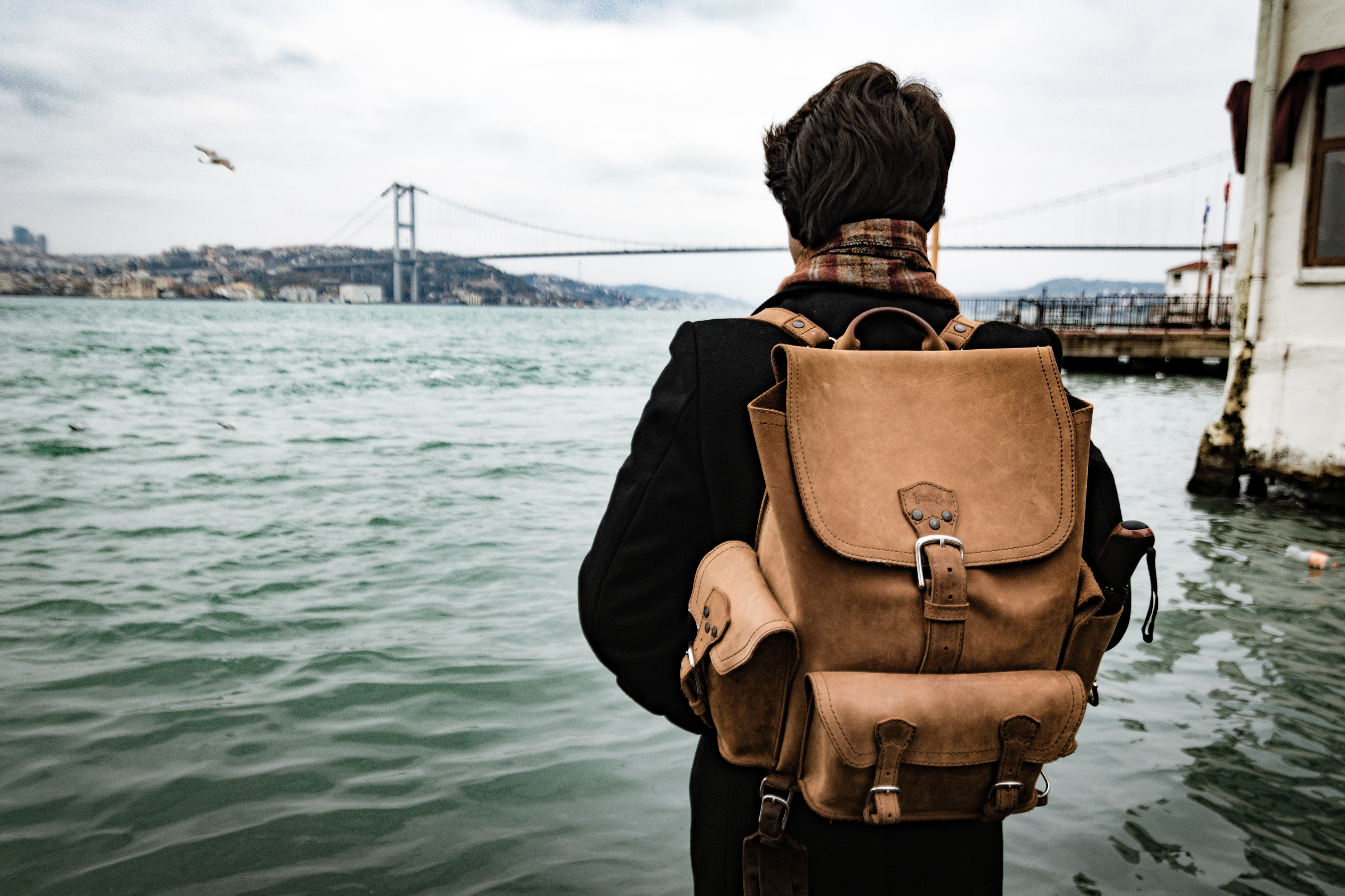 leather rucksack backpack on man by bridge
