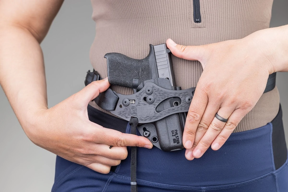 A person wearing leggings and an athletic top with no belt, positioning the PHLster Enigma faceplate at the waist.