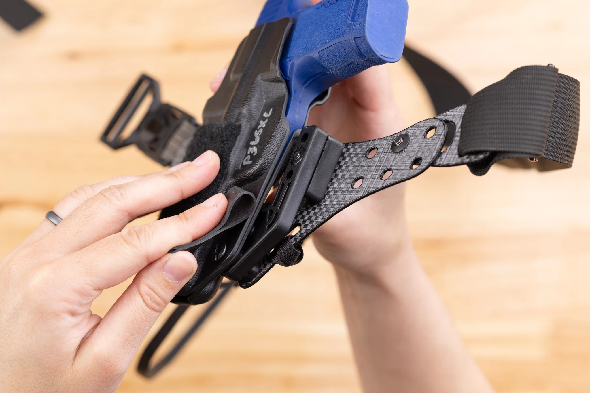 Photo of using a rubber band to tighten the screws holding the holster to the Enigma faceplate.