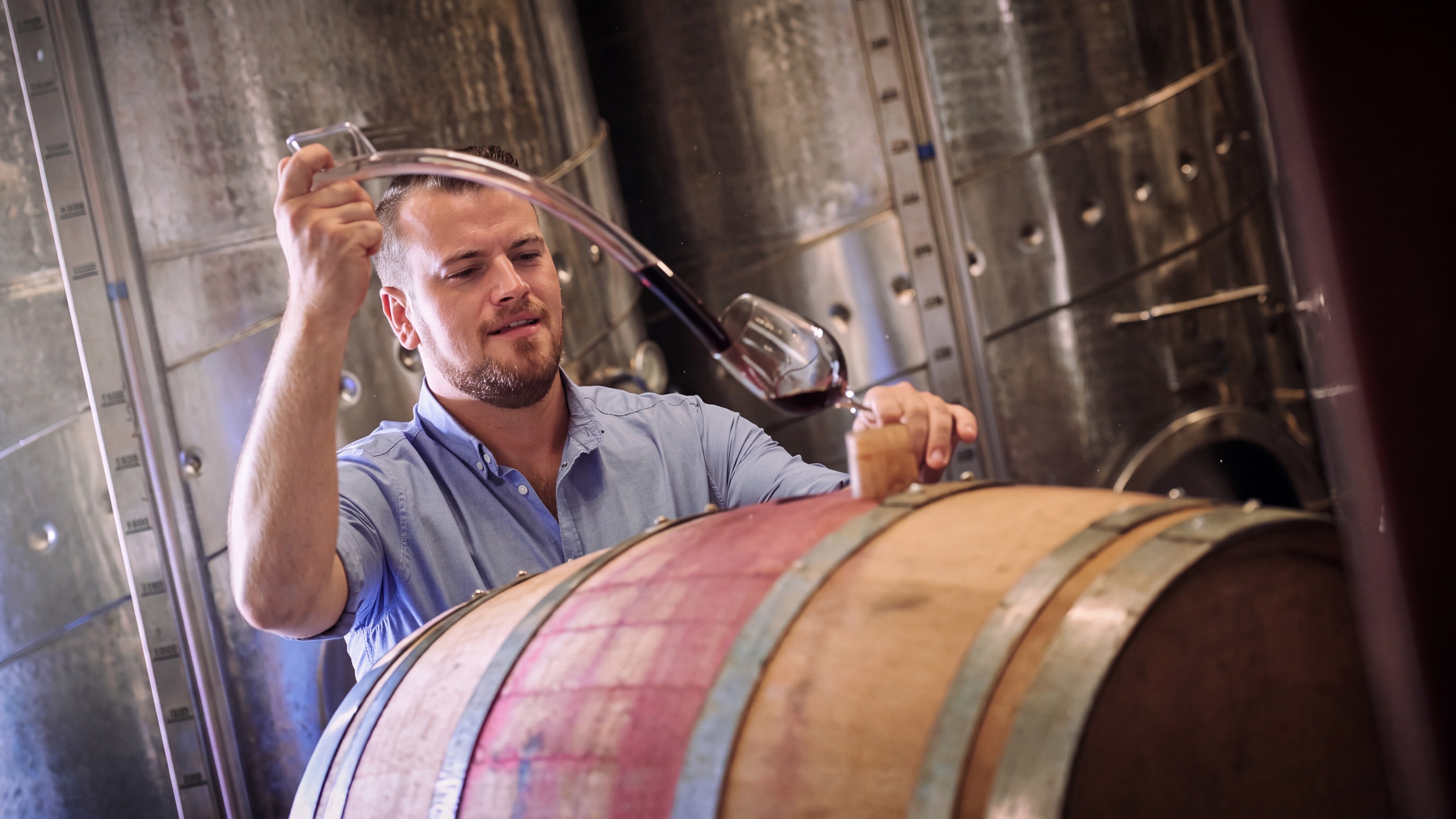 Editorial image of wine being sampled from a cellar barrel