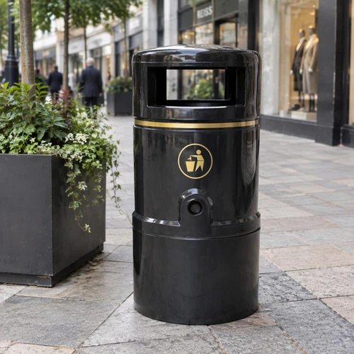 Roadware Grasmere 120 Litre Outdoor Heritage Litter Bin, black cylindrical street litter bin with gold trim and waste symbol displayed on a paved shopping street