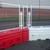 Oaklands Angle Mesh Hoarding Panel For RB22 Crash Barrier, white metal mesh fencing with white posts and red and white base barriers.