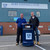 Roadware Derwent 120 Litre Outdoor Heritage Litter Bin, dark blue outdoor litter bin with a crest logo, placed outside Bury Football Club with two men standing beside it.