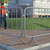 ZND 2.3m Galv Trade Crowd & Site Barrier, galvanized metal crowd control barrier on brick pavement with modern building and grass in background.