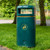 Roadware Coniston 90 Litre Outdoor Litter Bin, green outdoor trash can with a recycling symbol for waste disposal, located in a park setting with trees and grass.
