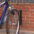 QMP 60 / 90 Degree Wall Mounted Bicycle Rack, black metal wall mount bike rack securing a mountain bike to a brick wall.