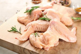 raw jumbo chicken wings on a wooden board, garnished with green sprigs