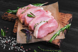 raw Boneless Pork Chops and rosemary on a wax paper
