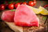 Yellowfin tuna steaks on a wood board with tomatoes and lemons