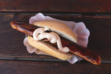 grilled bratwursts in bun topped with sriracha mayo