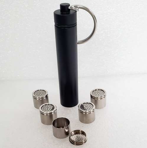 Black anodized aluminum Travel Caddy closed for Tinymight 2 Dosing Capsules with keychain split ring attached above in silver.  Dosing capsules spread out in front of caddy with one opened to show capsule lid.  