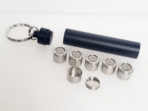 Dosing Capsule 6 Pack for the Arizer Solo/AirSeries removed from Travel Caddy Storage Tube in background with cap in upper left corner.  5 Dosing Capsules in middle row with caps and an individual cap in front with cap removed to show internals of the capsules.   Dosing Capsule 6 Pack for the Arizer Solo/AirSeries removed from Travel Caddy Storage Tube in background with cap in upper left corner.  5 Dosing Capsules in middle row with caps and an individual cap in front with cap removed to show internals of the capsules.