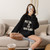 Model sitting on sofa with cell phone wearing long sleeved  black sweat shirt with  "Pet Hair Is The New Black" in the center.