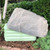 DekoRRa Model 117 faux rock cover placed over a green cable pedestal, seamlessly blending into a landscaped garden with shrubs and trees. View Product Image