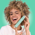 Mujer sonriendo mientras sostiene la pasta dental Coco Caribe, disfrutando del vibrante sabor caribeño.