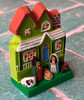 Angled view of miniature Salvadoran nativity house showing the red roof, front porch, Mary, Joseph, and Baby Jesus