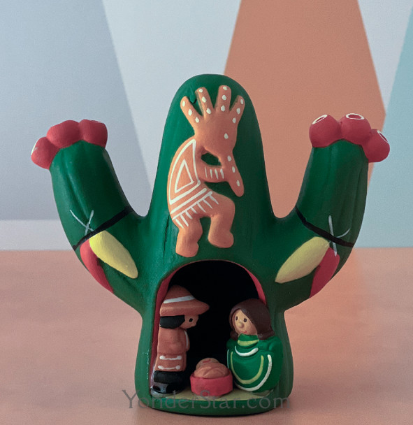 Handmade Peruvian nativity scene sheltered inside a green cactus with Kokopelli decoration, featuring the Holy Family in bright folk art colors.