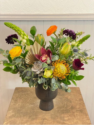 Organic Meadow
This super fun floral is packed with textures and tones. It includes a succulent, pincushion protea, and dried spear palm along with thistle and spring flowers. Our metallic gray vase gives it a stately look good for any occasion.
Seattle flower delivery by Juniper Flowers