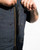 Close-up of a person wearing a blue denim jacket with a zipper, on a white background.