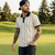 Man with tattoos wearing a striped shirt and cap on a golf course