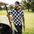 Man in a checkered shirt and cap standing next to a golf cart on a golf course.
