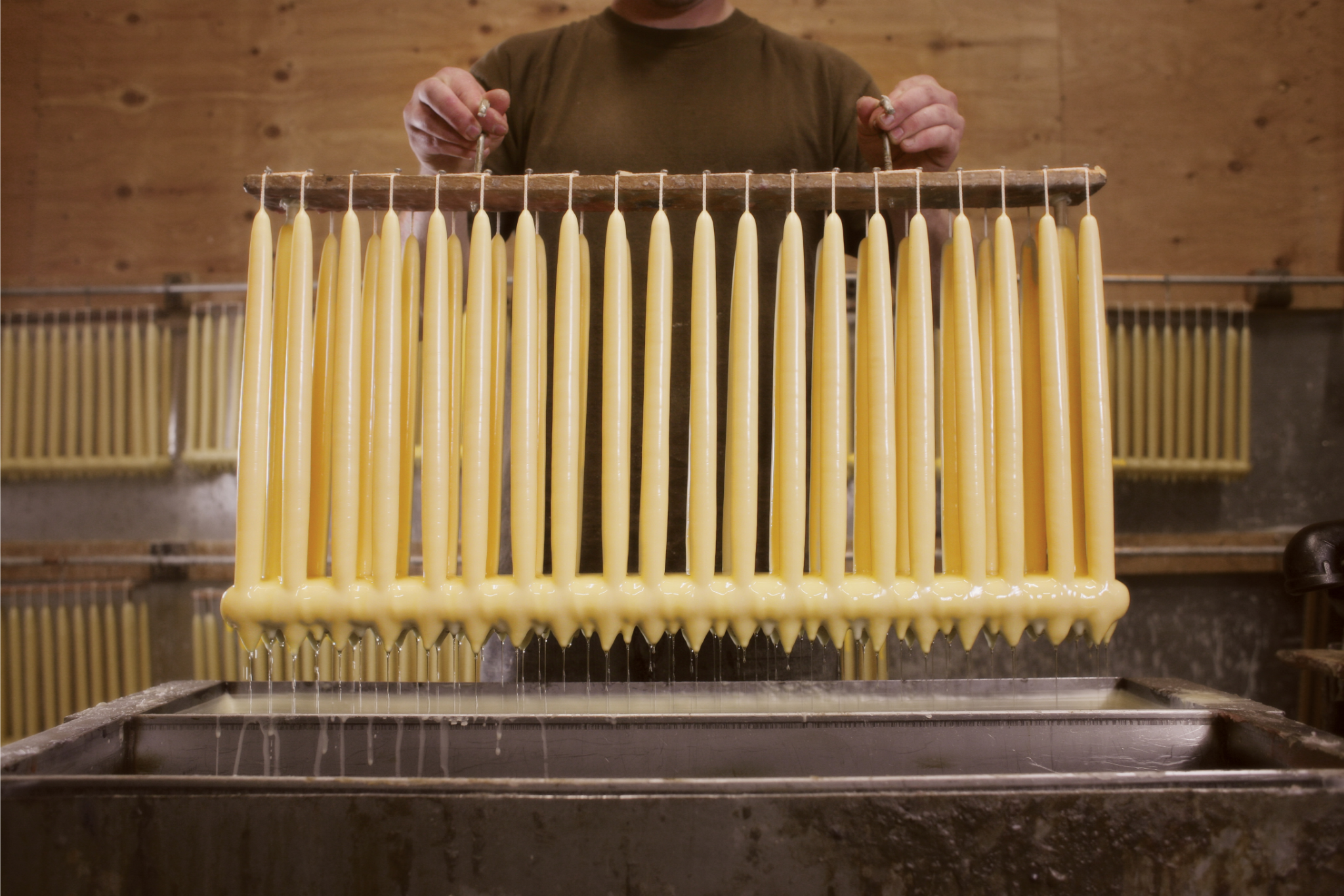 Hand dipping natural beeswax taper candles  