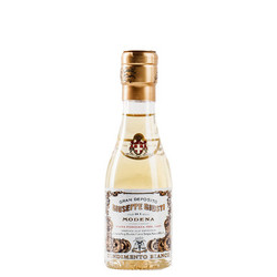 The image shows a bottle of "Gran Deposito Aceto Balsamico di Modena IGP" from Giuseppe Giusti. The bottle is clear, displaying the light-colored vinegar inside. It features a traditional, elegant shape with a narrow neck and a gold cap. The label is intricate and classic, with details in black and gold that emphasize the prestigious heritage of the Giusti brand, which dates back to 1605. This product presentation highlights the quality and tradition associated with Giuseppe Giusti vinegars, suitable for culinary enthusiasts looking for authentic balsamic vinegar from Modena.