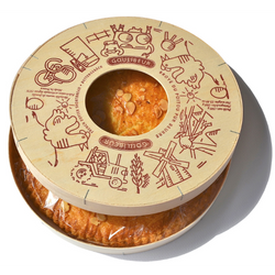 A tastefully designed wooden box containing a large cookie with a distinctive hole in the middle. The box features whimsical illustrations of farm animals including a tractor, a hen, and a cow, along with the esteemed brand name 'Goulibeur'. An artisanal French delight, boasting a crumbly texture, decadent buttery flavor, and exquisite attention to detail.