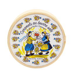 A round wooden box of La Maison d'Armorine Salted Butter Caramels weighing 7oz. The lid features a charming illustration with traditional French design elements, emphasizing the artisanal and gourmet nature of the product. The caramels inside are individually wrapped, showcasing their quality and attention to detail.