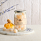 Clear glass jar labeled “Boules de Miel — Lavender Honey Drops,” filled with pale, sugar-dust coated round candies resting inside. Clear glass jar labeled “Boules de Miel — Lavender Honey Drops,” filled with pale, sugar-dust coated round candies resting inside.