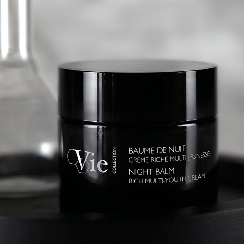Night Balm Rich Multi-Youth Cream next to a beaker.