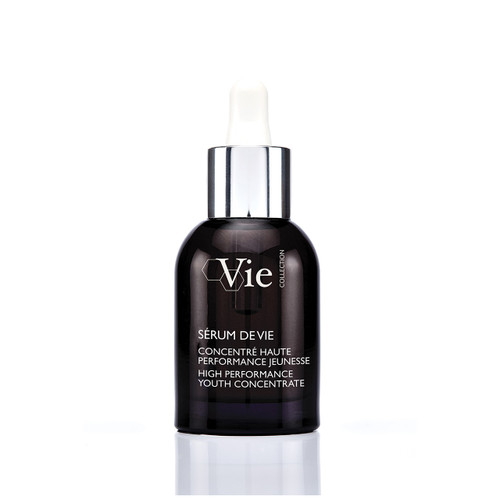 A dark glass serum bottle with a dropper cap, labeled "Sérum de Vie," resting on a textured stone surface.