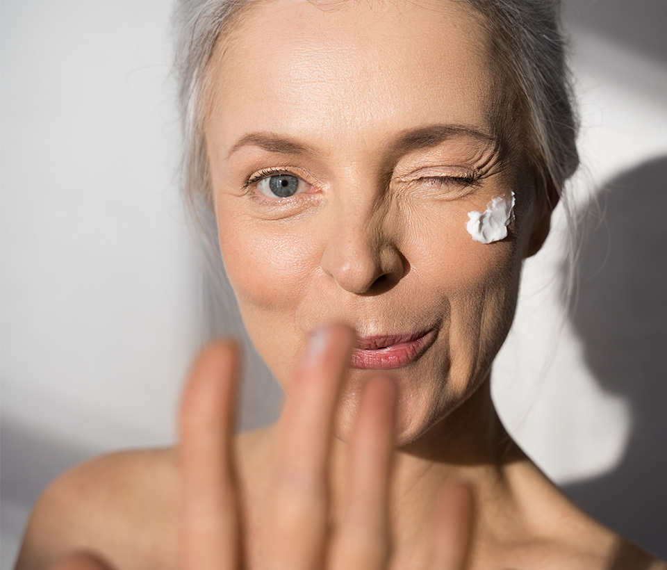 Woman winking at the camera with a swipe of cream across her cheek. 