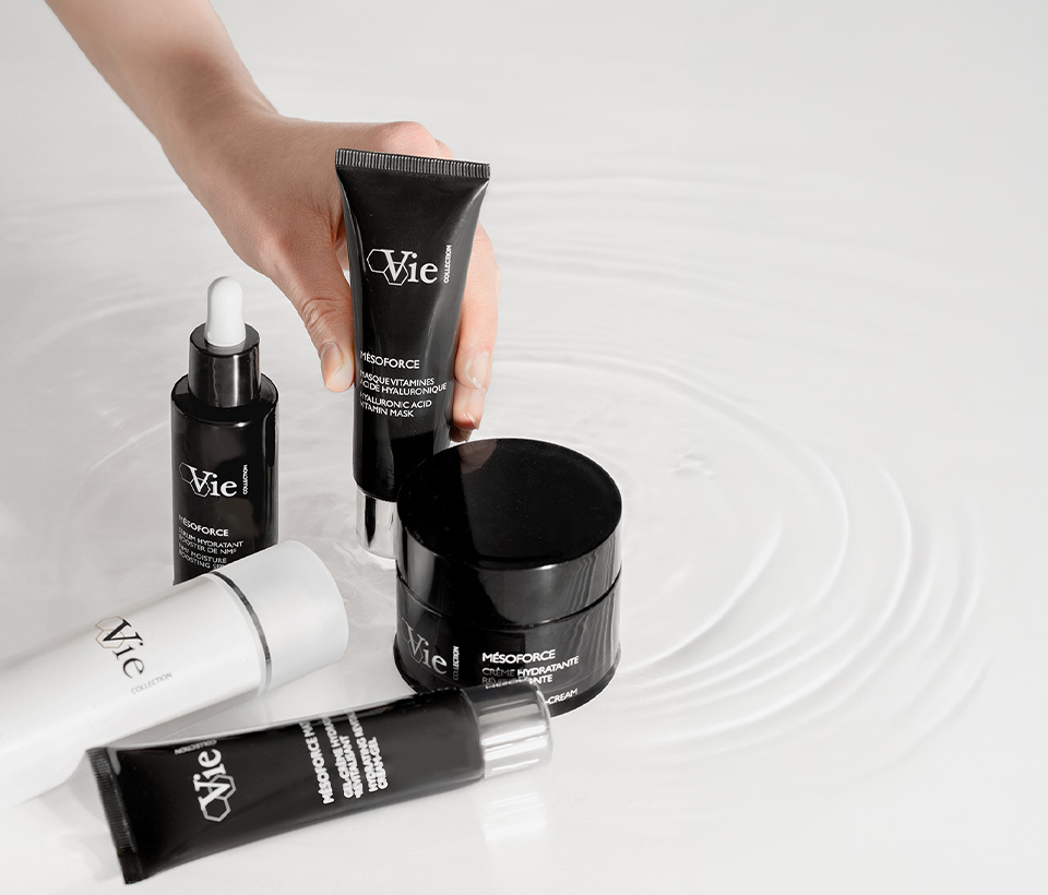 A woman places the Mesoforce Hyaluronic Acid Vitamin Mask down on a table next to the Mesoforce Serum, cream, Mattifying Cream Gel, and new Mesoforce Lotion.