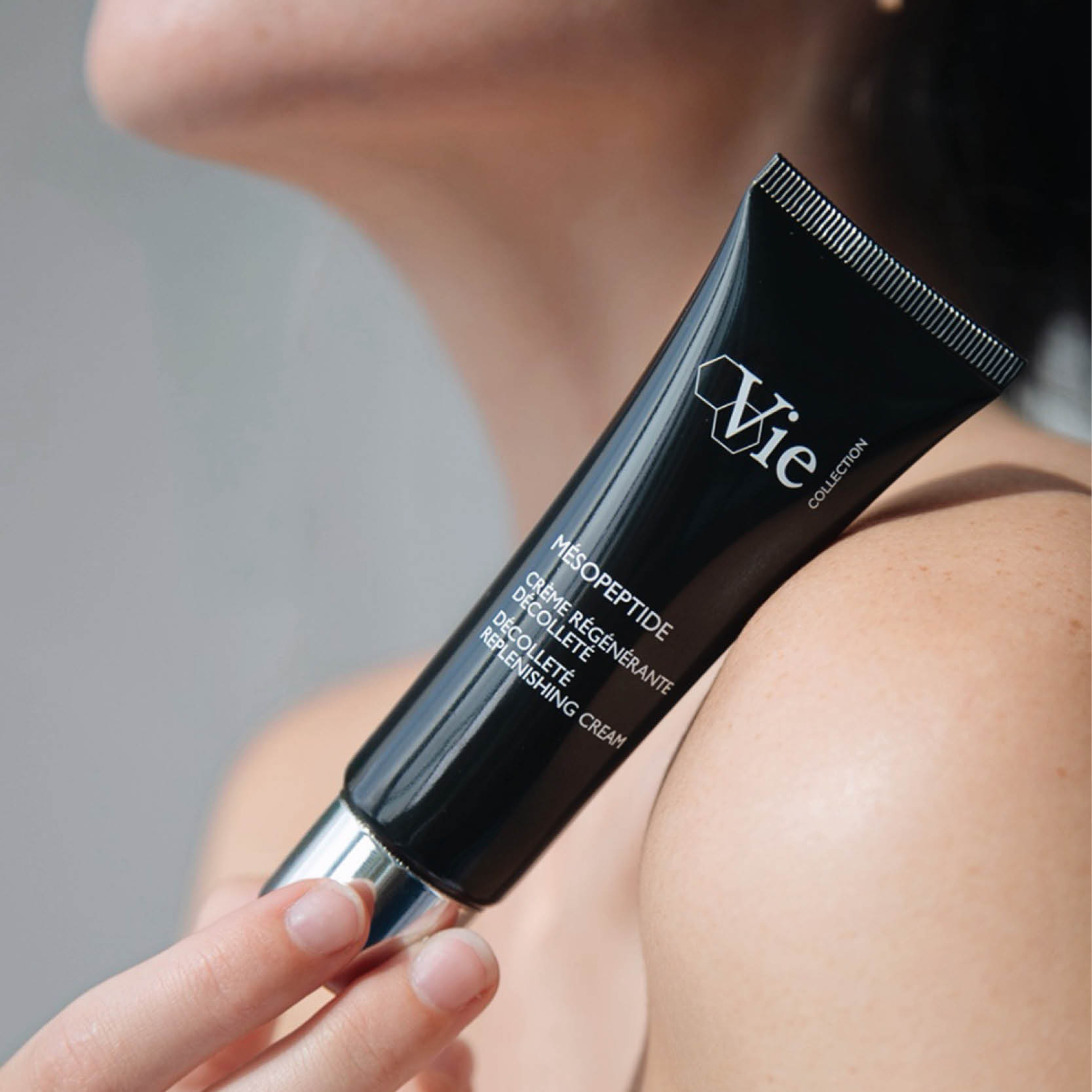 Mesopeptide Decollete Replenishing Cream, held against a woman's shoulder.